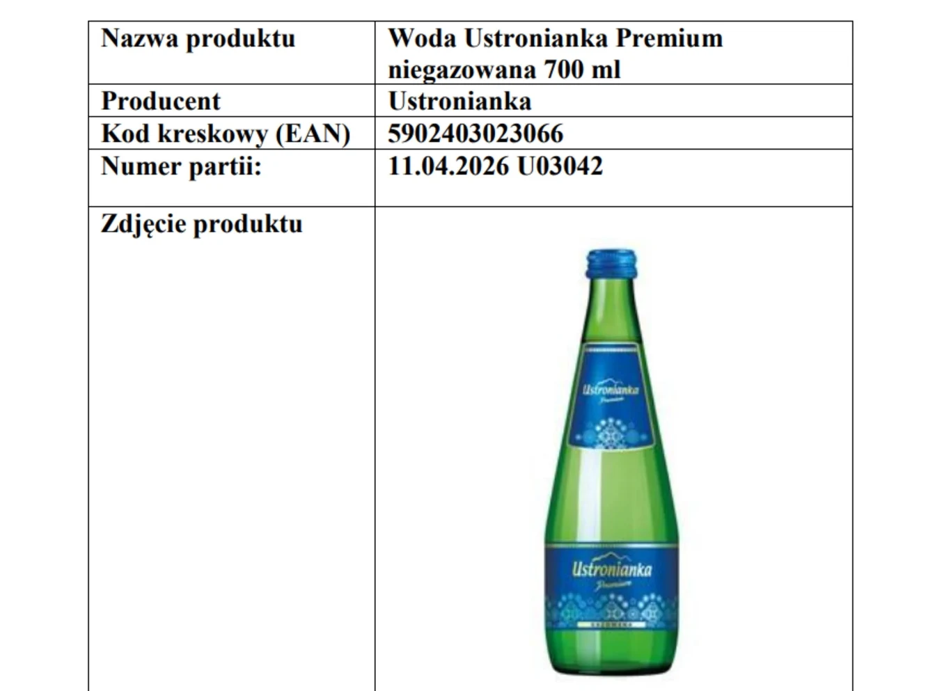 Butelka wody mineralnej Ustronianka Premium niegazowana o pojemności 700 ml, zielone szkło z niebieską etykietą, zakrętka niebieska, w tle arkusz informacyjny z danymi produktu, producent, kod kreskowy oraz numer partii.
