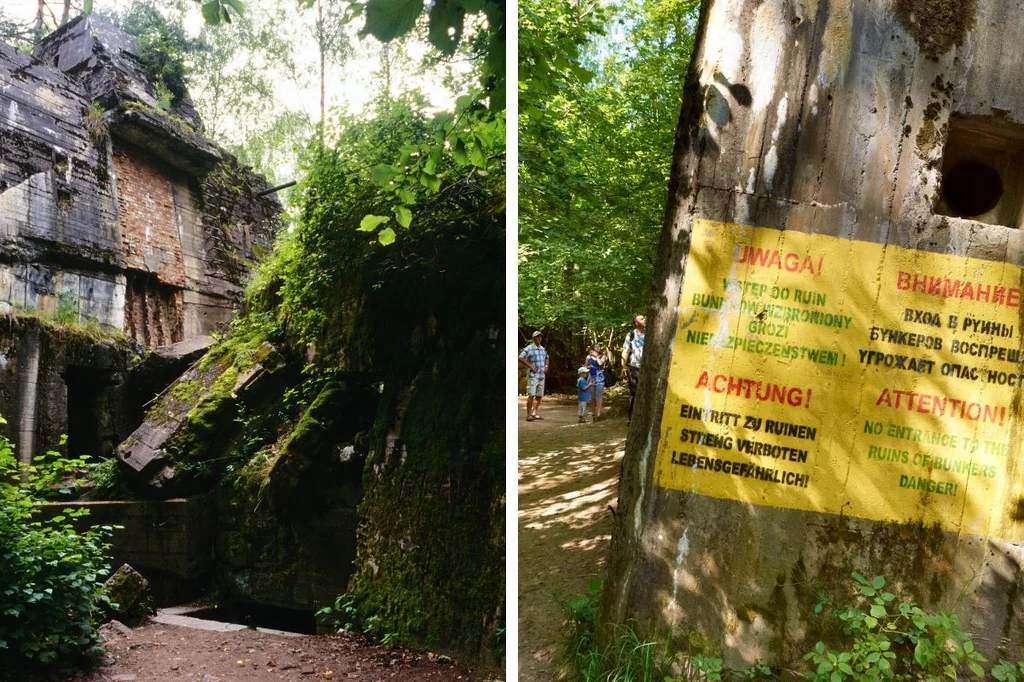 Ruiny betonowej budowli otoczone zielenią lasu oraz żółta tablica ostrzegawcza z napisem o niebezpieczeństwie, ostrzegająca w kilku językach przed wchodzeniem do ruin. W oddali widoczne są osoby zwiedzające teren.