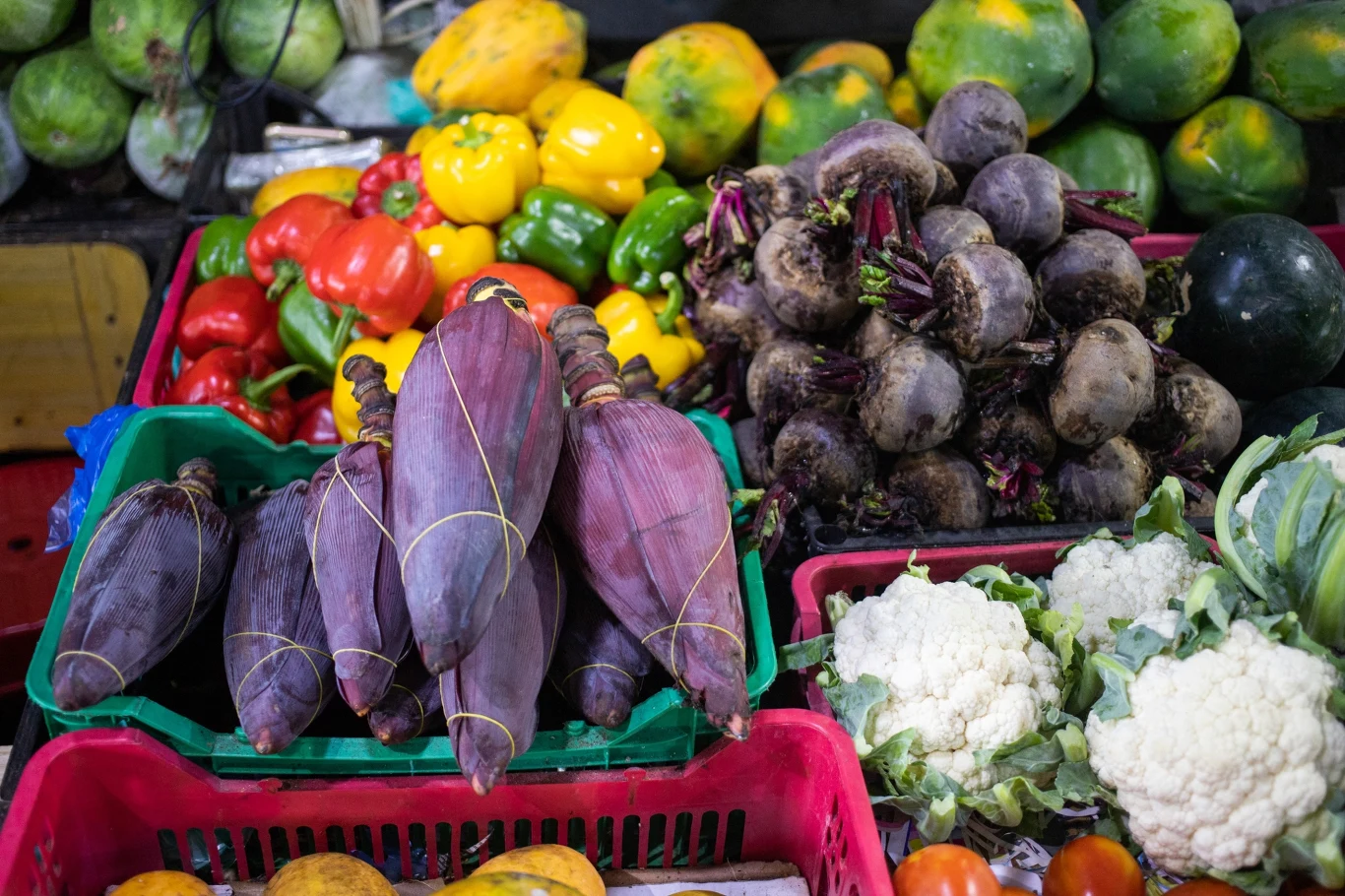 Młodzi czasem decydują się na droższą, ekologiczną żywność od lokalnych dostawców Różnorodne warzywa ułożone w plastikowych skrzynkach, w tym papryki, bananowce, buraki, kalafiory i papaje, wyeksponowane obok siebie na targowym stoisku.