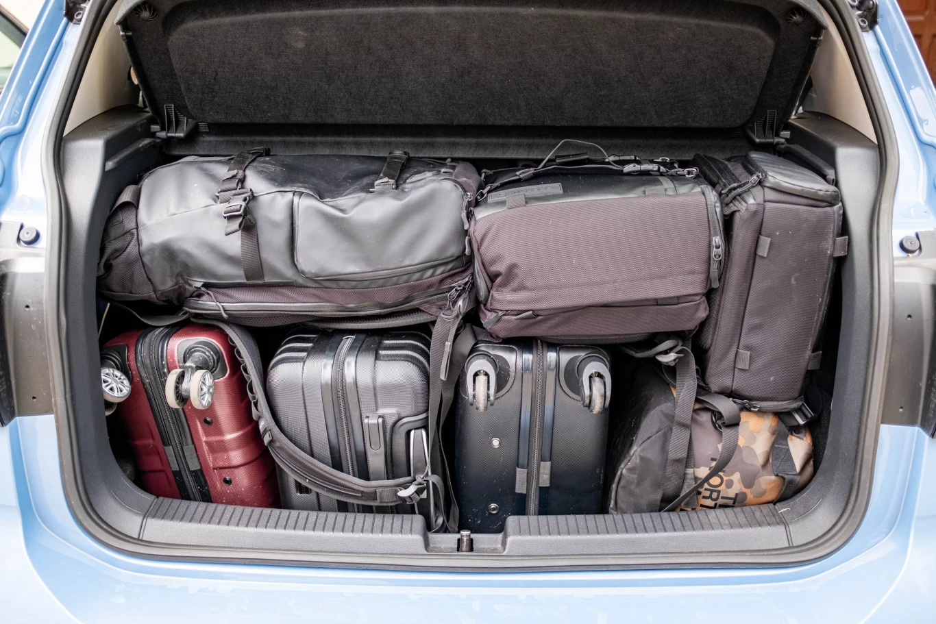 Pojemność bagażnika to maksymalnie 455 litrów przy rozłożonej kanapie, minimalnie wynosi 385 l. Jak widać - może pomieścić więcej niż się wydaje. Bagażnik samochodu wypełniony różnej wielkości walizkami i torbami podróżnymi zapakowanymi aż po samą klapę.