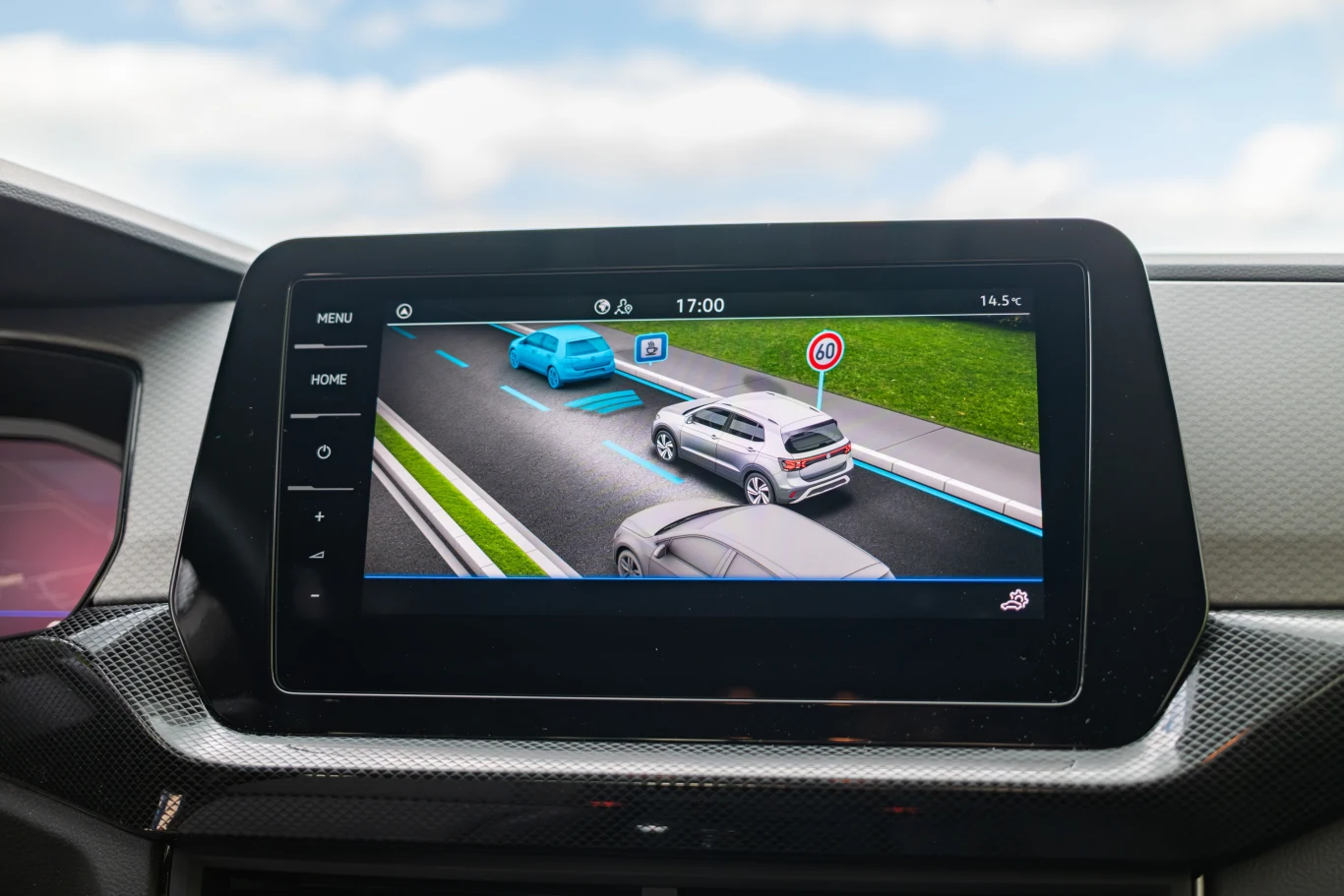 Nie wszystkie systemy asystujące są w standardzie, ale te podstawowe tak, czyli układ czytania znaków, wykrywania przeszkód z przodu oraz obiektów w martwym polu. Ekran komputera pokładowego samochodu wyświetlający wizualizację pojazdów na drodze, znak ograniczenia prędkości oraz system asystujący prowadzącego, wskazujący obecność innych samochodów na pasie ruchu.