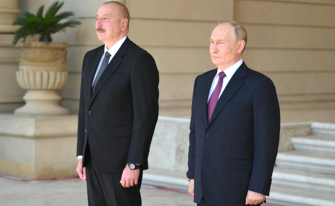 Władimir Putin i Ilham Alijew Dwóch mężczyzn w garniturach stoi obok siebie na tle monumentalnej architektury z widoczną donicą i rośliną w tle, atmosfera oficjalna.