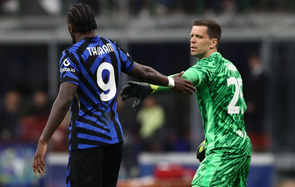 Wojciech Szczęsny i Marcus Thuram Dwóch piłkarzy na boisku podczas meczu, jeden w niebiesko-czarnej koszulce z numerem 9, drugi w zielonym stroju bramkarskim wyciąga rękę w jego stronę, widoczna intensywna atmosfera sportowej rywalizacji.