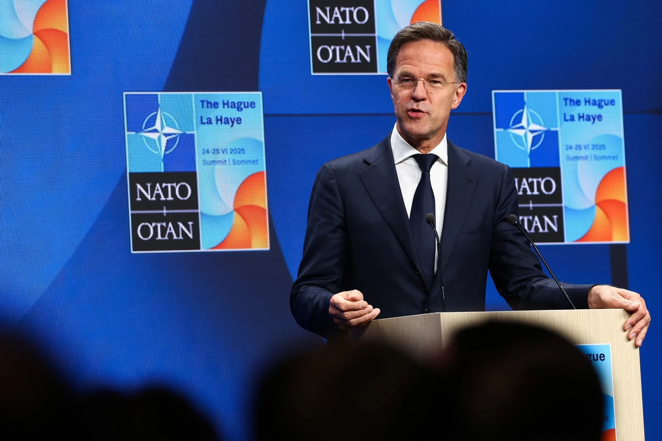 Mark Rutte reaguje na decyzję USA ws. Ukrainy Mężczyzna w garniturze przemawia na mównicy podczas szczytu NATO w Hadze, w tle logotypy NATO oraz plansza informacyjna dotycząca miejsca i daty wydarzenia.