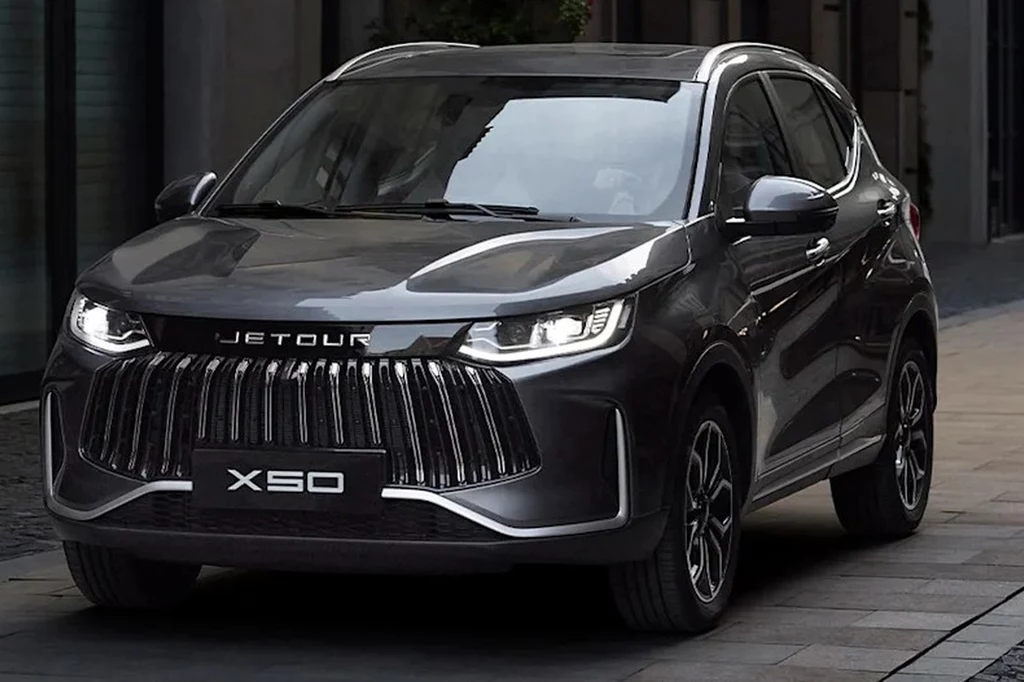 czarny samochód osobowy typu SUV marki Jetour X50 zaparkowany na ulicy, wyraźny grill i nowoczesne reflektory podkreślają dynamiczny wygląd auta, jasne odbicia światła na karoserii