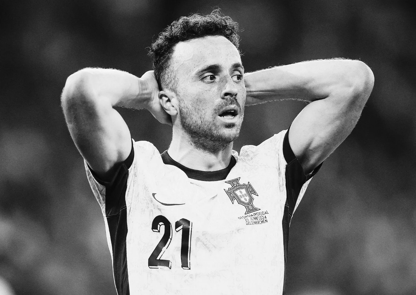 Piłkarz w koszulce reprezentacji Portugalii z numerem 21 na piersi trzyma ręce za głową, wyrażając emocje związane z przebiegiem meczu.