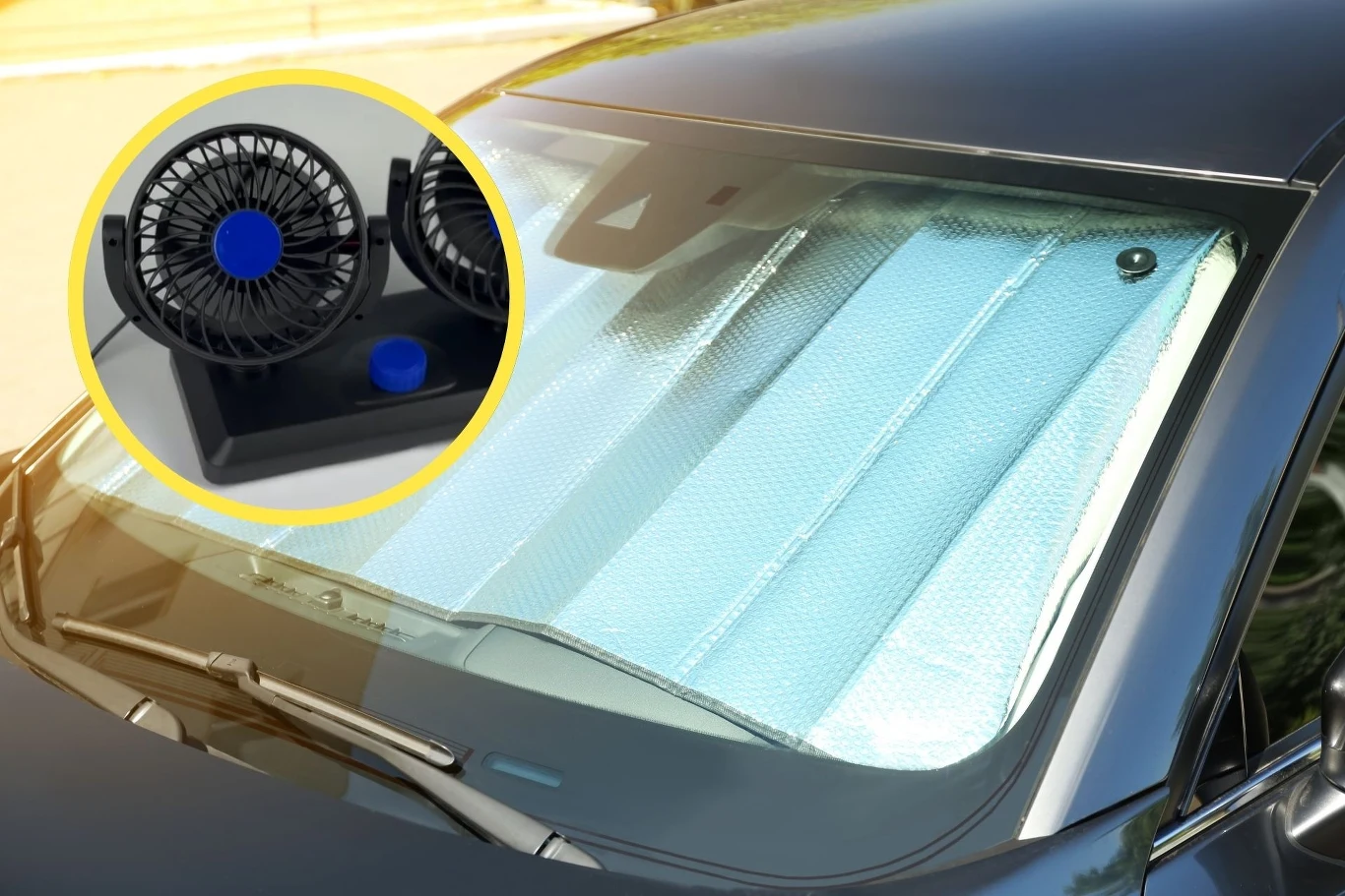 Jakie gadżety pozwolą komfortowo podróżować w upalne dni? Samochód z zamontowaną na przedniej szybie matą przeciwsłoneczną, w lewym górnym rogu widoczna powiększona grafika podwójnego wentylatora samochodowego.