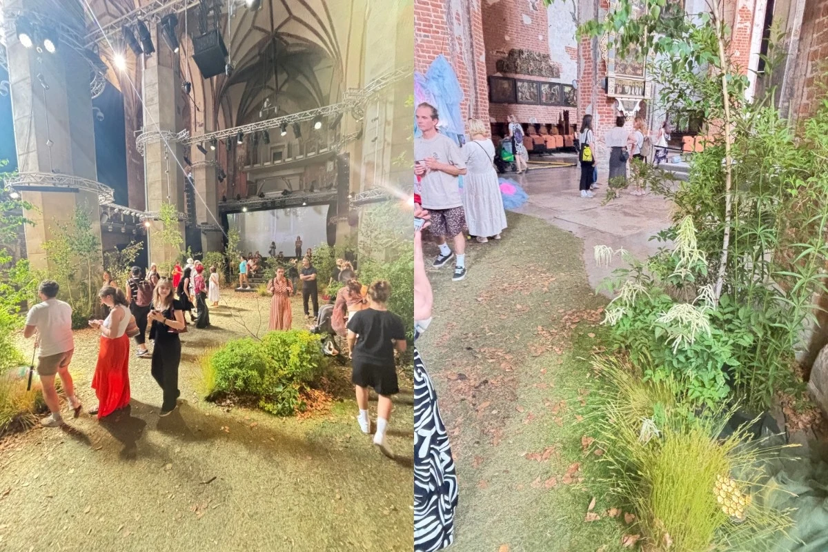 Duża hala z elementami zieleni i dekoracji, liczne osoby spacerujące lub rozmawiające w eleganckiej, otwartej przestrzeni z wysokimi sklepieniami i ceglaną architekturą, część osób w tle obserwuje wydarzenie lub instalację artystyczną.