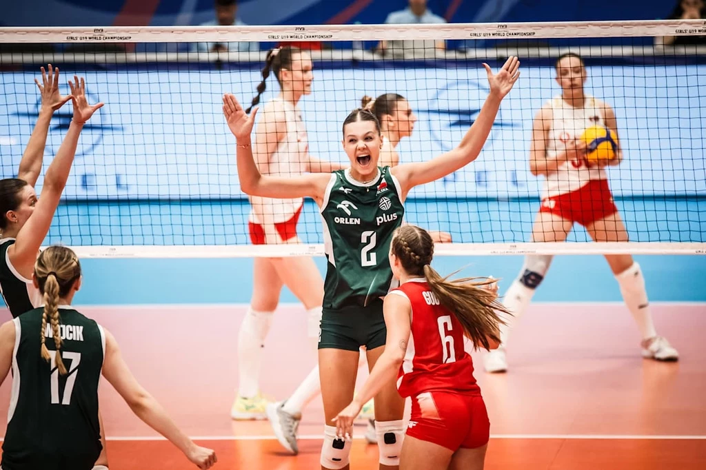 Polskie siatkarki podczas meczu z Turcją na MŚ U19 Zawodniczki drużyn siatkarskich podczas zaciętej rywalizacji na boisku, jedna z siatkarek w ciemnozielonym stroju z podniesionymi rękami okazuje radość, wokół niej inne zawodniczki, jedna z nich w czerwonym stroju z numerem 6, tłum w tle rozmyty.