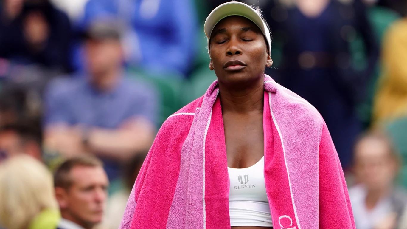 Venus Williams przez wiele lat walczyła z mięśniakami Zawodniczka tenisowa ubrana w sportowy top i czapkę, z zamkniętymi oczami i różowym ręcznikiem na ramionach, stoi w skupieniu na tle rozmytej publiczności.
