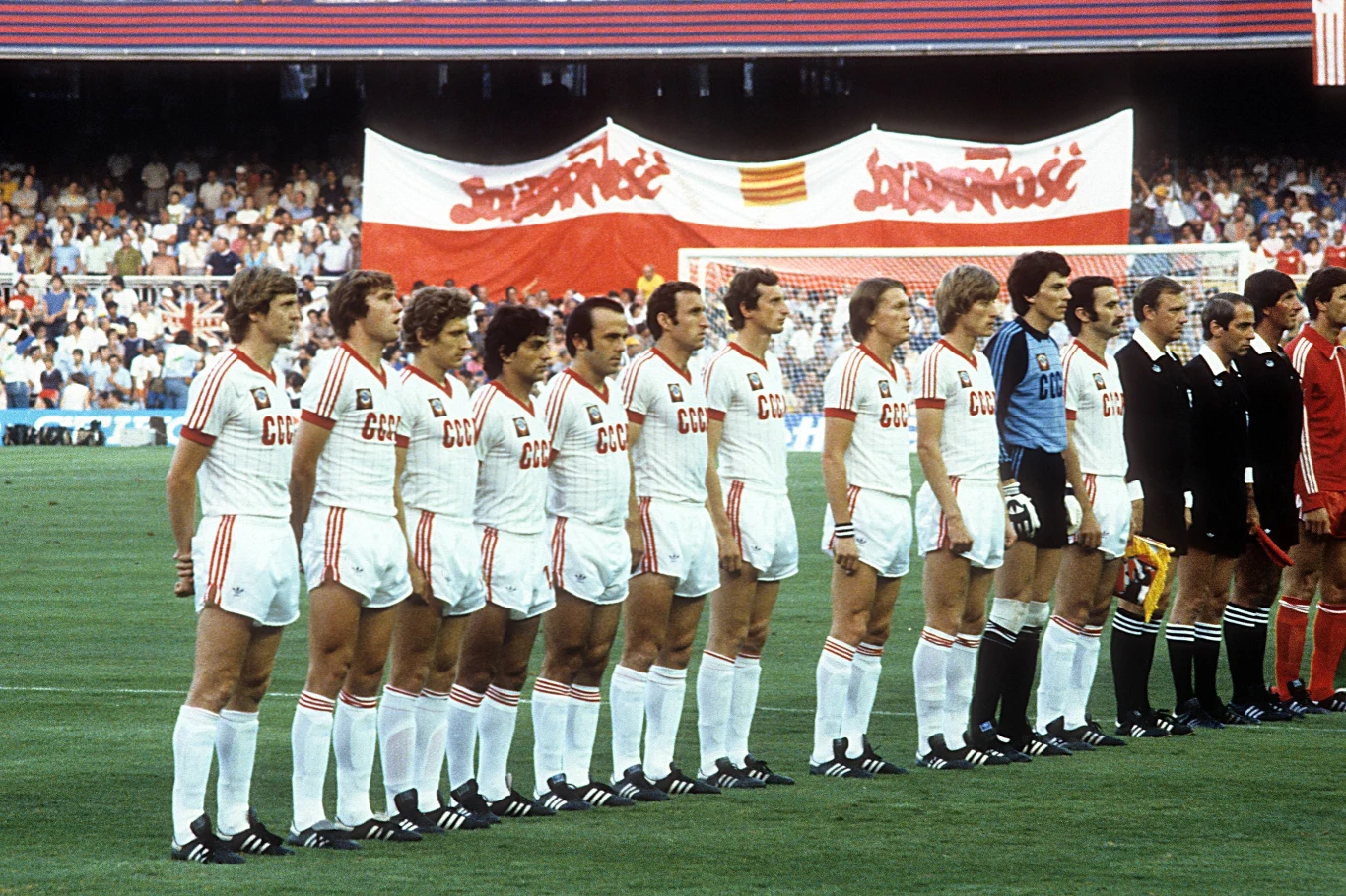 Reprezentacja ZSRR, a za nią... Polska flaga ze znakami "Solidarności". W Moskwie to nie mogło się spodobać Polska drużyna piłkarska stoi w szeregu podczas ceremonii przed meczem, wszyscy zawodnicy ubrani są w białe stroje z czerwonymi napisami. W tle widać transparenty z napisem Solidarność oraz zgromadzonych kibiców na trybunach.
