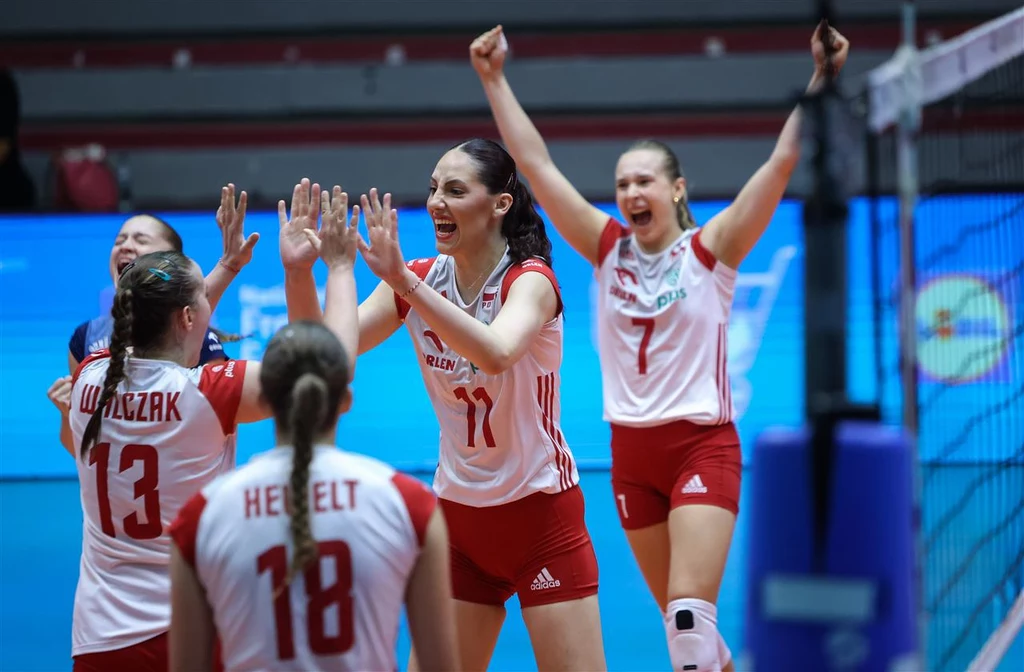 Polskie siatkarki U-21 Zawodniczki drużyny siatkarskiej w biało-czerwonych strojach świętują zdobycie punktu, unosząc ręce i wyrażając radość, na pierwszym planie widoczne są emocje oraz interakcje sportowe pomiędzy członkiniami zespołu.