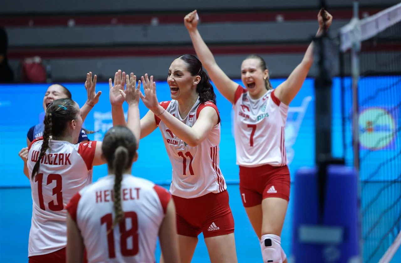 Polskie siatkarki U-21 Zawodniczki drużyny siatkarskiej w biało-czerwonych strojach świętują zdobycie punktu, unosząc ręce i wyrażając radość, na pierwszym planie widoczne są emocje oraz interakcje sportowe pomiędzy członkiniami zespołu.
