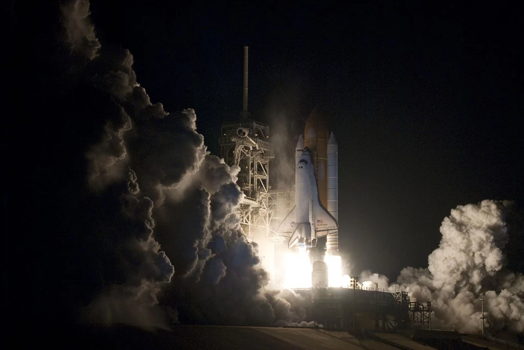 Start misji STS-130. Wahadłowiec NASA Endeavour dostarczył na ISS moduł Cupola. Start wahadłowca kosmicznego odbywający się nocą, intensywne kłęby dymu i jasne światło wylotów silników rakietowych podkreślają dynamiczny moment startu i technologiczną potęgę konstrukcji.