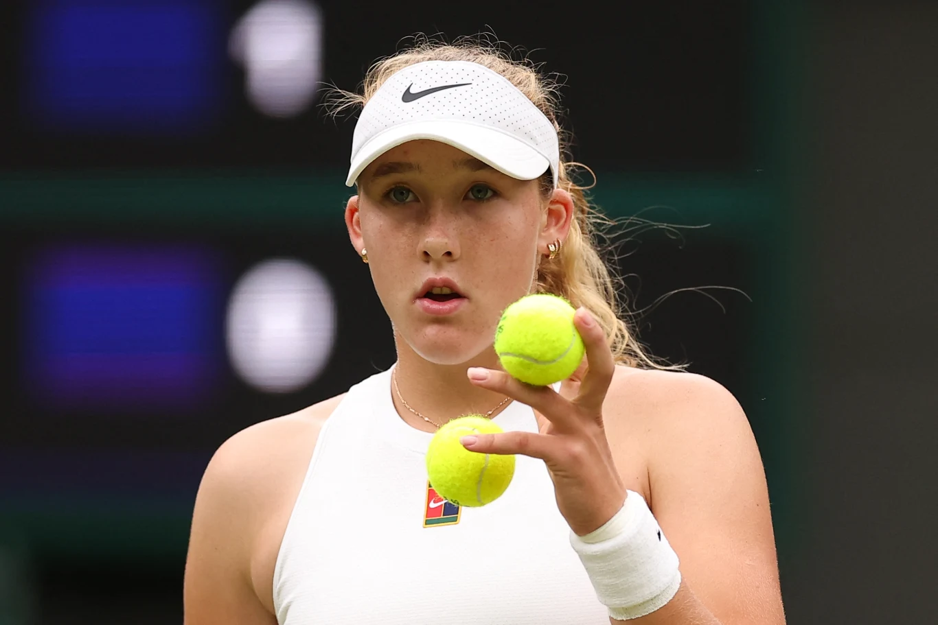 Mirra Andriejewa rywalizowała z Hailey Baptiste o awans do czwartej rundy Wimbledonu Młoda tenisistka w białym stroju sportowym i czapce trzymająca dwie piłki tenisowe, skupiona przed rozegraniem kolejnej akcji.