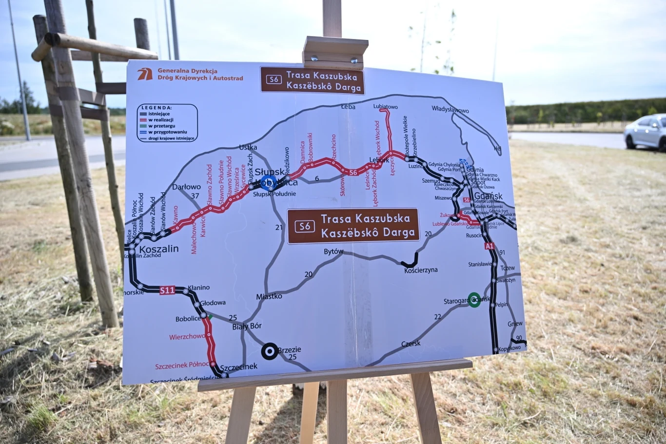 Taki będzie miał przebieg budowana jeszcze Trasa Kaszubska, czyli droga ekspresowa S6 Mapa Trasy Kaszubskiej ustawiona na sztaludze na tle pobocza drogi, przedstawiająca przebieg drogi S6 oraz położenie większych miast i węzłów komunikacyjnych regionu pomorskiego.