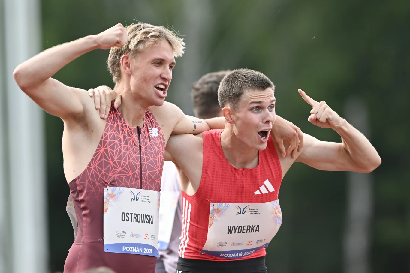 Filip Ostrowski i Maciej Wyderka wypełnili minimum na mistrzostwa świata Dwóch młodych lekkoatletów w sportowych strojach celebruje sukces na stadionie, okazując radość i podnosząc ręce w geście zwycięstwa, mają na piersiach przypięte numery startowe z nazwiskami.