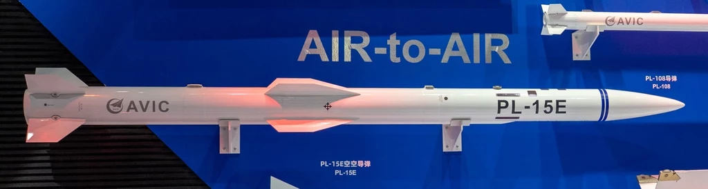 Model pocisku PL-15E produkcji Aviation Industry Corporation of China Pocisk powietrze-powietrze PL-15E zaprezentowany na tle niebieskiej tablicy informacyjnej z oznaczeniem producenta AVIC oraz szczegółami technicznymi.