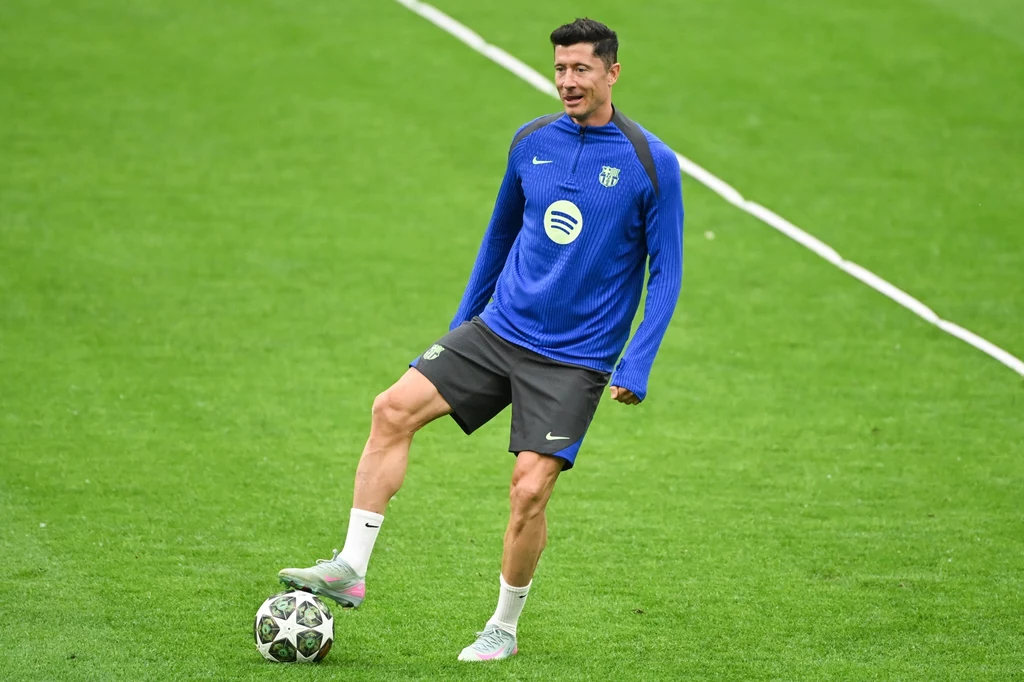 Robert Lewandowski, FC Barcelona Piłkarz w niebieskim stroju sportowym z logo Barcelony podczas treningu na zielonej murawie, kontrolujący piłkę w ruchu.