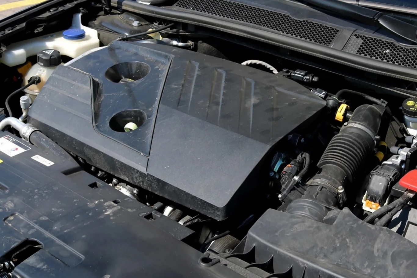 Silnik 1.5 BlueHDi z poważną wadą. Widok silnika samochodowego z pokrywą oraz widocznymi elementami układu chłodzenia i przewodami powietrznymi.