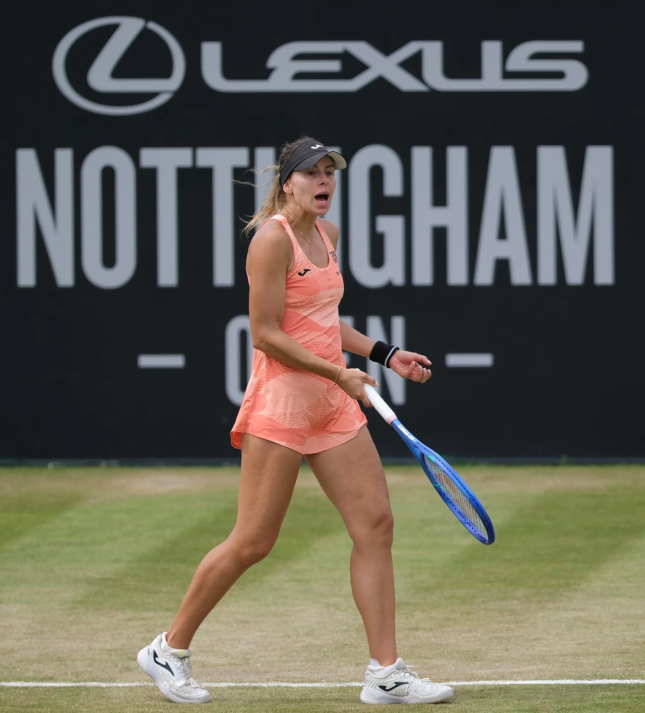 Magda Linette Tenisistka w pomarańczowym stroju sportowym z rakietą w ręku podczas meczu na trawiastym korcie, w tle tablica z napisem Nottingham Open i logo Lexus.