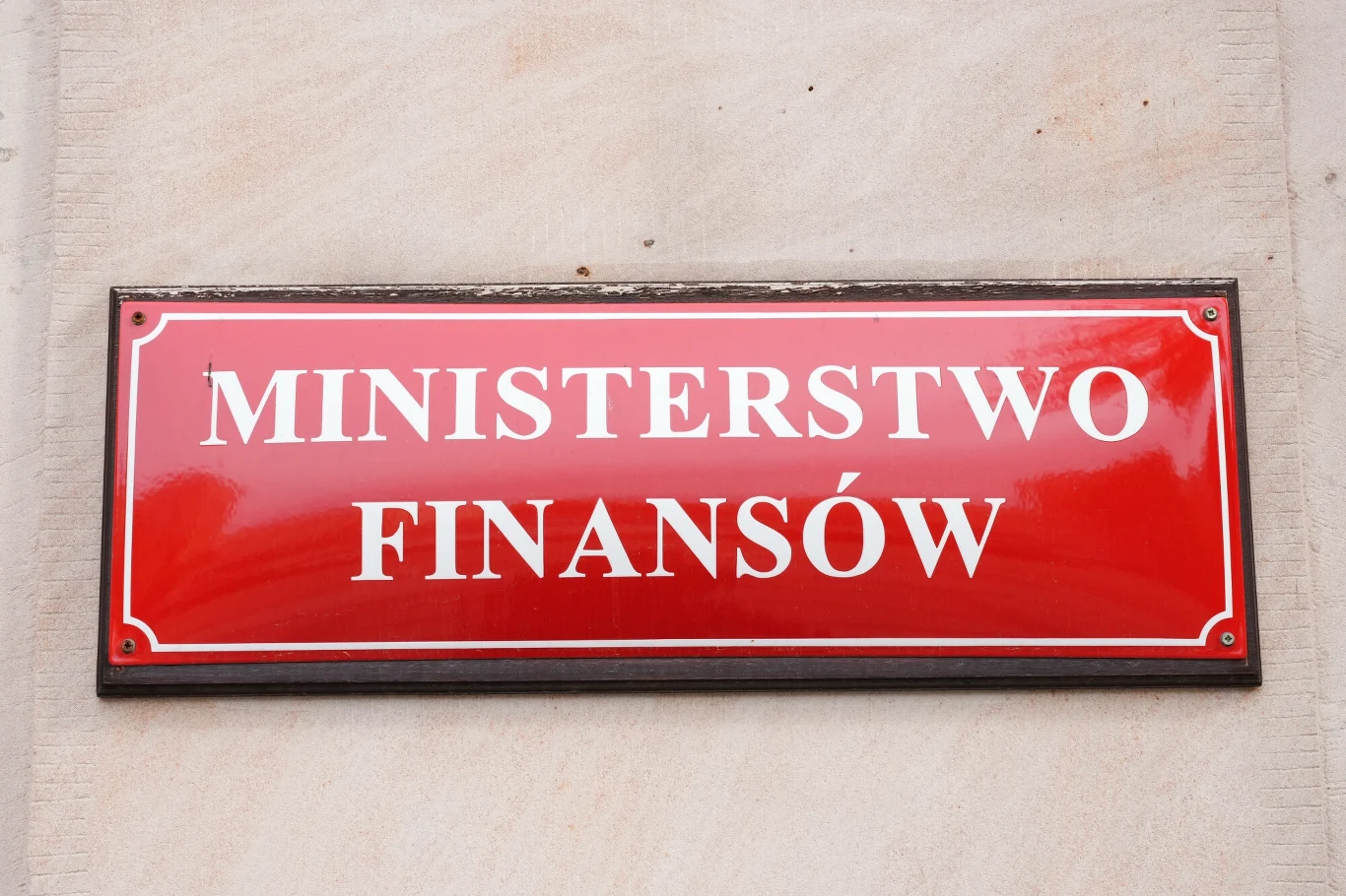 Ministerstwo Finansów ostrzega przed nowym oszustwem Czerwona tablica z białym napisem Ministerstwo Finansów na jasnej ścianie budynku.