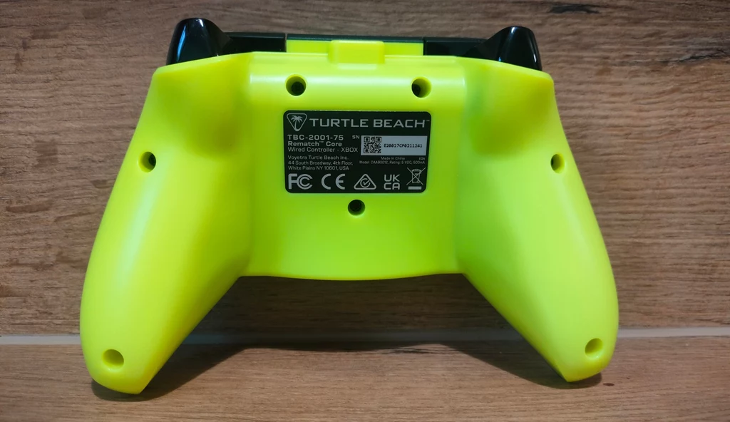 Żółty kontroler do gier marki Turtle Beach, widoczny od tyłu, z wyraźną etykietą zawierającą informacje techniczne i oznaczenia certyfikatów.