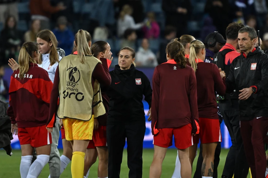 Reprezentacja Polski po porażce ze Szwecją na Euro 2025 Zawodniczki kobiecej reprezentacji Polski w piłce nożnej zgromadzone w grupie na murawie, ubrane w oficjalne stroje sportowe z widocznym logo polskiej federacji i napisami, trener oraz członkowie sztabu w tle.