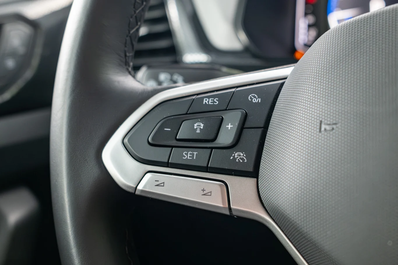 Przyciski na kierownicy są rozmieszczone ergonomicznie, a ich największa zaleta to ta, że są klasycznymi, fizycznymi przyciskami, których nie wciśniemy przez przypadek. Fragment kierownicy samochodu z widocznym zestawem przycisków do obsługi tempomatu oraz innych funkcji pojazdu, wykończenie w kolorze czarnym i srebrnym.