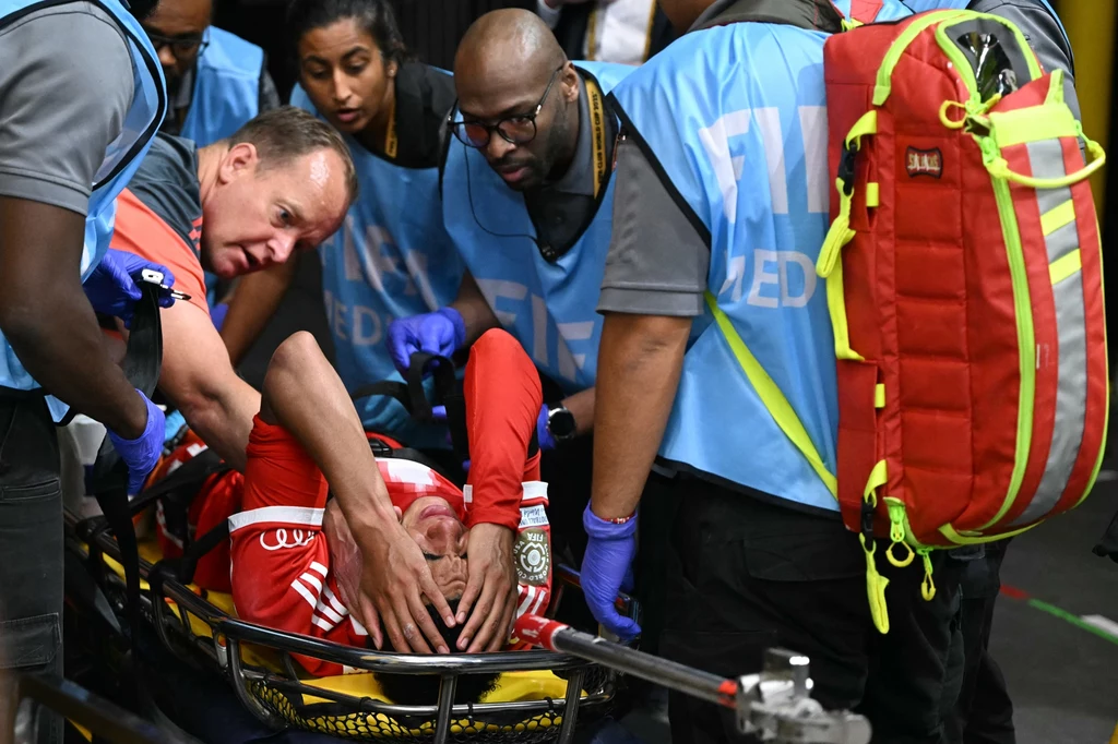 Jamal Musiala już w drodze do szpitala Zespół ratowników otacza rannego sportowca leżącego na noszach, udzielając mu pierwszej pomocy podczas wydarzenia sportowego, widoczne są profesjonalne stroje i sprzęt medyczny.