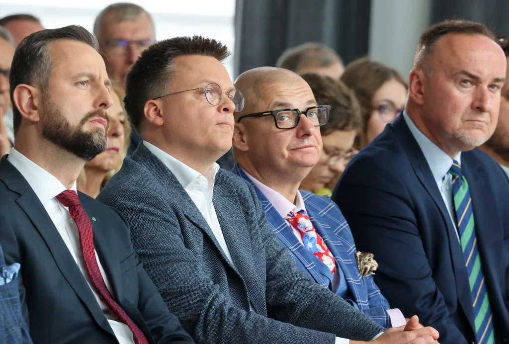 Od lewej: Władysław Kosiniak-Kamysz, Szymon Hołownia, Michał Kamiński, Michał Kobosko Czterech elegancko ubranych mężczyzn siedzi w pierwszym rzędzie podczas oficjalnego wydarzenia, uważnie obserwując prezentację lub wystąpienie.