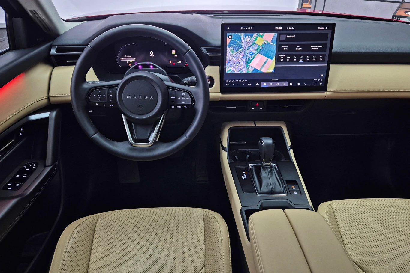 Wnętrze Mazdy CX-5 zmieniło się nie do poznania - całość obsługi przeniesiono na centralny ekran Nowoczesne wnętrze samochodu z jasnymi skórzanymi fotelami, kierownicą z logo marki Mazda i dużym wyświetlaczem systemu multimedialnego z nawigacją GPS.