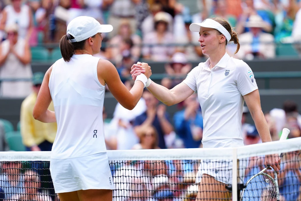 Iga Świątek i Ludmiła Samsonowa po ćwierćfinale Wimbledonu Dwie tenisistki w białych sportowych strojach ściskają sobie dłonie nad siatką na korcie tenisowym, wyrażając wzajemny szacunek po zakończonym meczu, w tle widownia obserwująca sytuację.