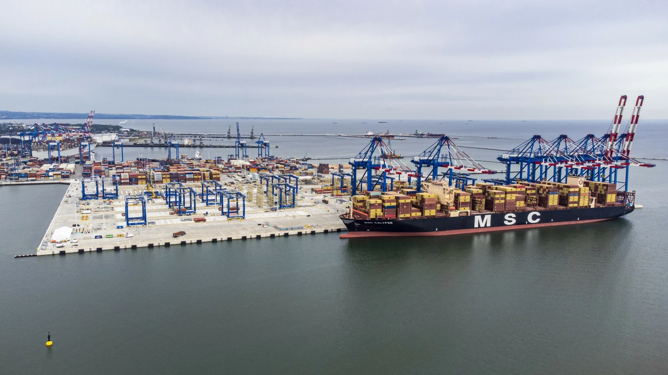 Nowy terminal T3 w Baltic Hub w Gdańsku Ogromny kontenerowiec firmy MSC przycumowany w nowoczesnym porcie przeładunkowym, wokół widoczne setki kolorowych kontenerów, suwnice portowe oraz infrastruktura nabrzeża rozciągająca się wzdłuż wybrzeża.