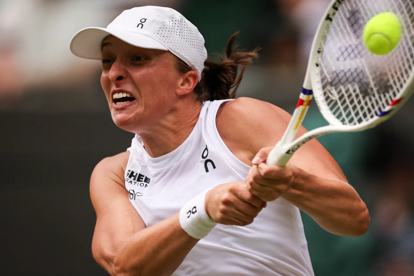 Iga Świątek Sportowiec uderzający piłkę tenisową rakietą, dynamiczny wyraz twarzy, białe sportowe ubranie, widoczny ruch oraz intensywna koncentracja podczas gry.