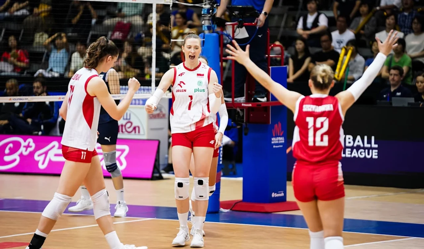 Polskie siatkarki podczas meczu Ligi Narodów 2025 Zawodniczki w biało-czerwonych strojach na boisku do siatkówki cieszą się po udanej akcji, jedna z nich stoi zwrócona do koleżanek z uniesionymi ramionami, w tle widać kibiców i elementy wyposażenia hali sportowej.