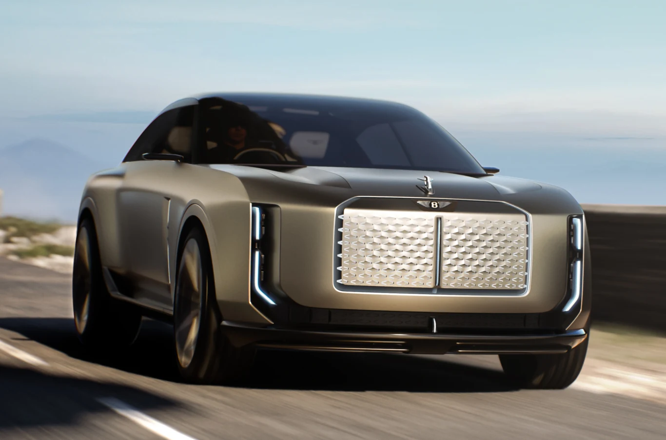 Prototyp Bentley EXP 15 zaprezentowany w nowym studio projektowym w Crewe. Nowoczesny luksusowy samochód z dużą, wyrazistą chromowaną atrapą chłodnicy oraz zintegrowanymi przednimi światłami LED, jadący po gładkiej, asfaltowej drodze w słoneczny dzień.