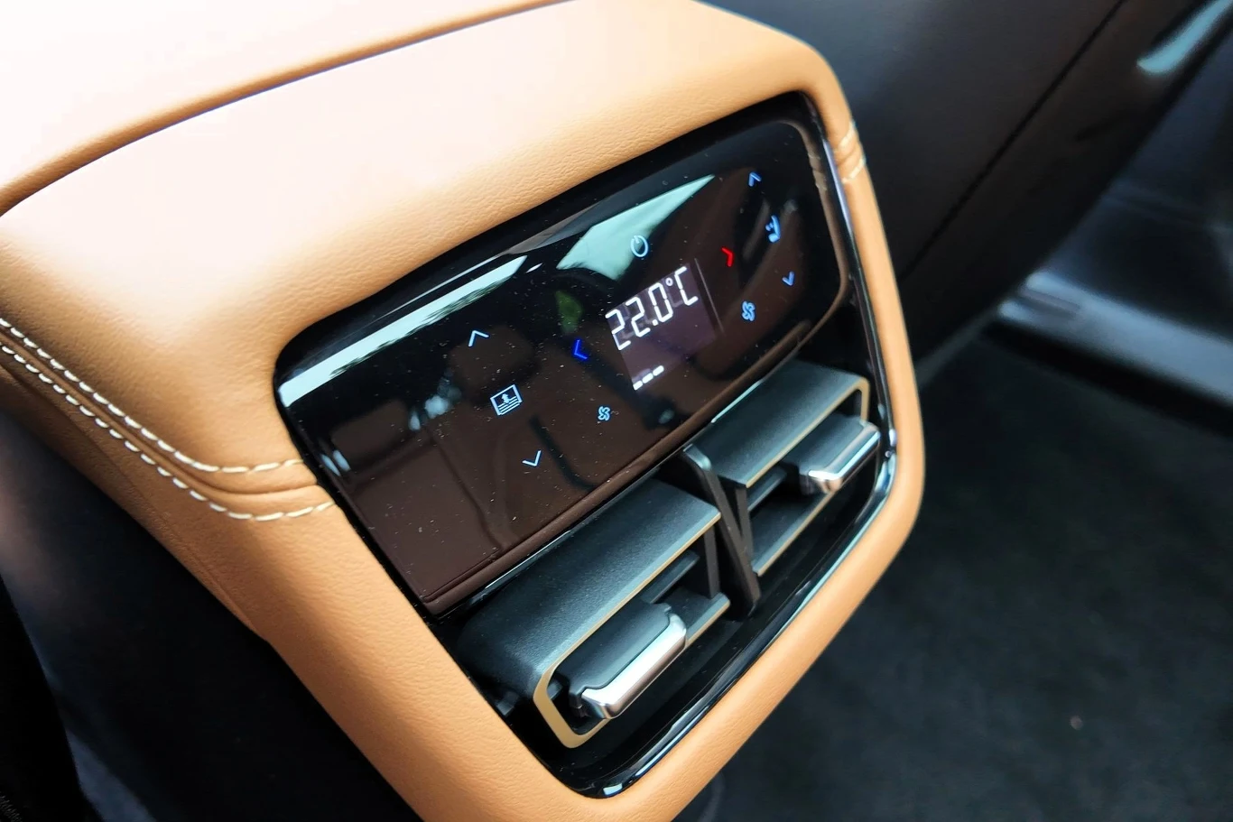 Za pomocą specjalnego panelu pasażerowie z tyłu mogą sterować klimatyzacją czy przesuwać fotel pasażera z przodu. Panel sterowania klimatyzacją w samochodzie, z brązowo-czarnym wykończeniem wnętrza, czytelnym wyświetlaczem elektronicznym pokazującym temperaturę 22°C oraz dwoma prostokątnymi nawiewami powietrza.