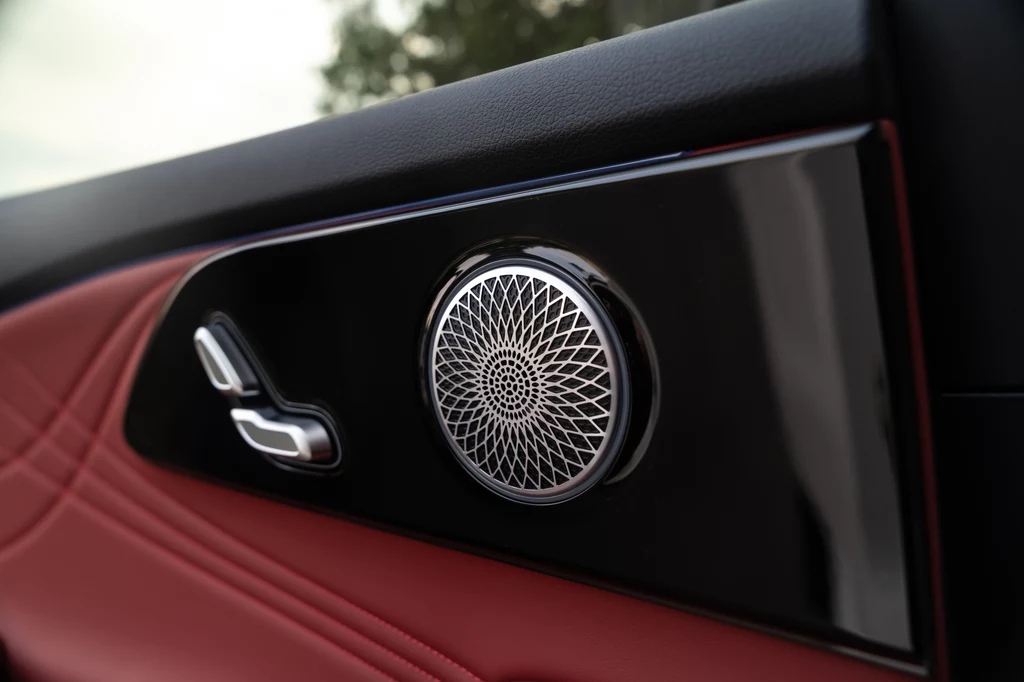 Omoda 9 Panel drzwiowy samochodu z głośnikiem premium o geometrycznym wzorze oraz przyciskami do regulacji fotela, wykończony czarnym i czerwonym materiałem.