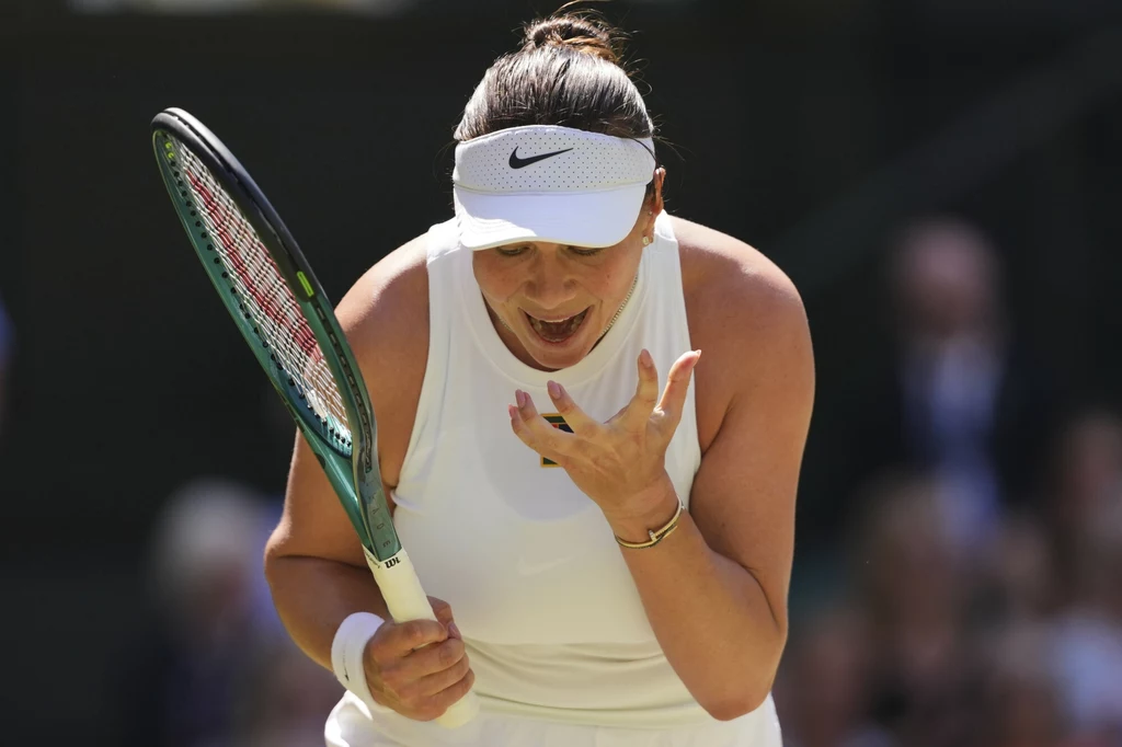 Amanda Anisimowa, 10.07.2025 r. Tenisistka w białym stroju sportowym z opaską na głowie wyraża silne emocje podczas meczu, trzymając rakietę w jednej dłoni, a drugą ręką ukazując gest frustracji lub zaskoczenia.