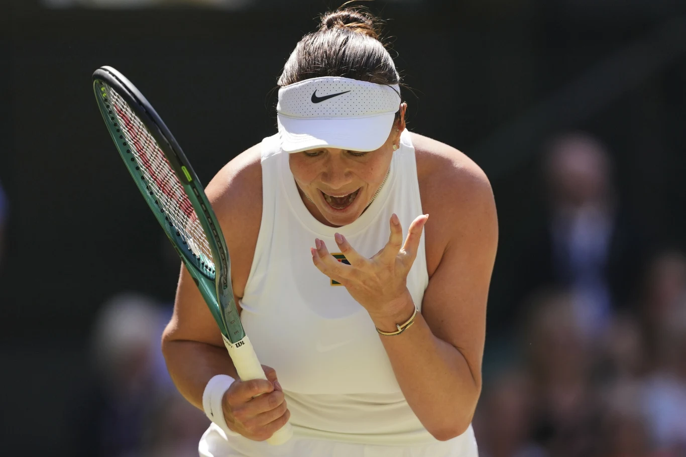 Amanda Anisimowa, 10.07.2025 r. Tenisistka w białym stroju sportowym z opaską na głowie wyraża silne emocje podczas meczu, trzymając rakietę w jednej dłoni, a drugą ręką ukazując gest frustracji lub zaskoczenia.