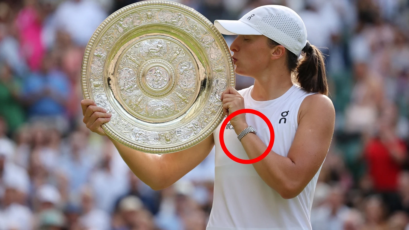 Tenisistka w białej sportowej sukience i czapce całuje srebrną tacę – trofeum zwycięzcy turnieju, trzymając je obiema dłońmi, z wyeksponowaną bransoletką na nadgarstku, w tle rozmyta, dopingująca publiczność.