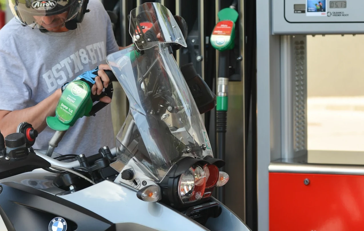 Jak zatankować motocykl? Motocykl marki BMW tankowany na stacji benzynowej, osoba trzyma dyszę podającą paliwo, widoczne elementy dystrybutora oraz wyraźne oznaczenia paliwa.