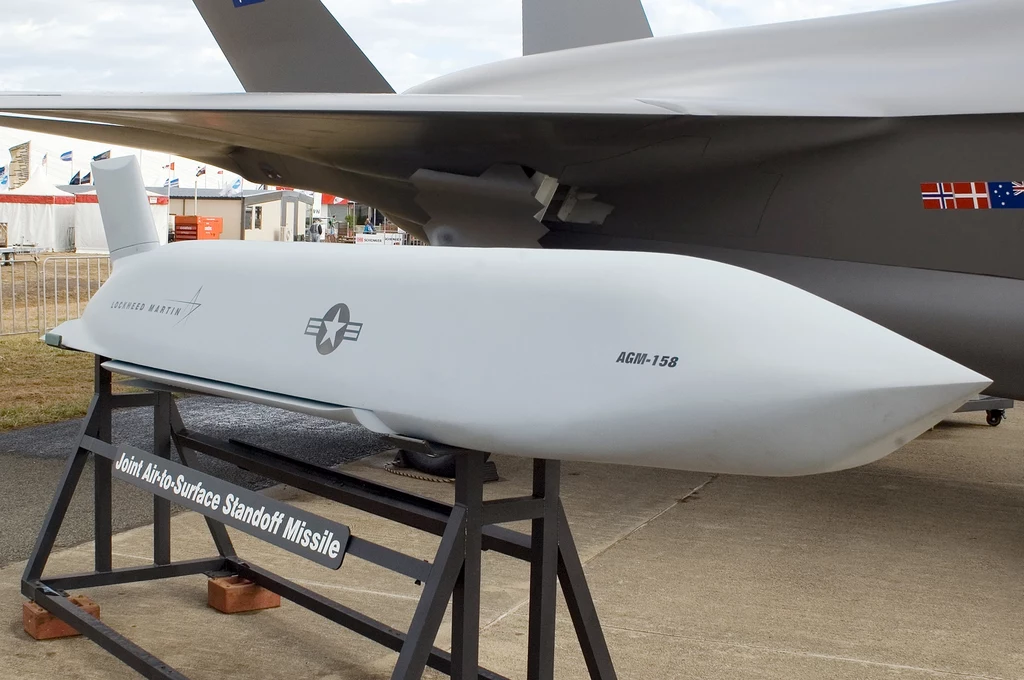 Pocisk manewrujący AGM-158 Joint Air-to-Surface Standoff Missile na ekspozycji obok samolotu wojskowego, oznaczony logo Lockheed Martin oraz symbolem Sił Powietrznych Stanów Zjednoczonych.