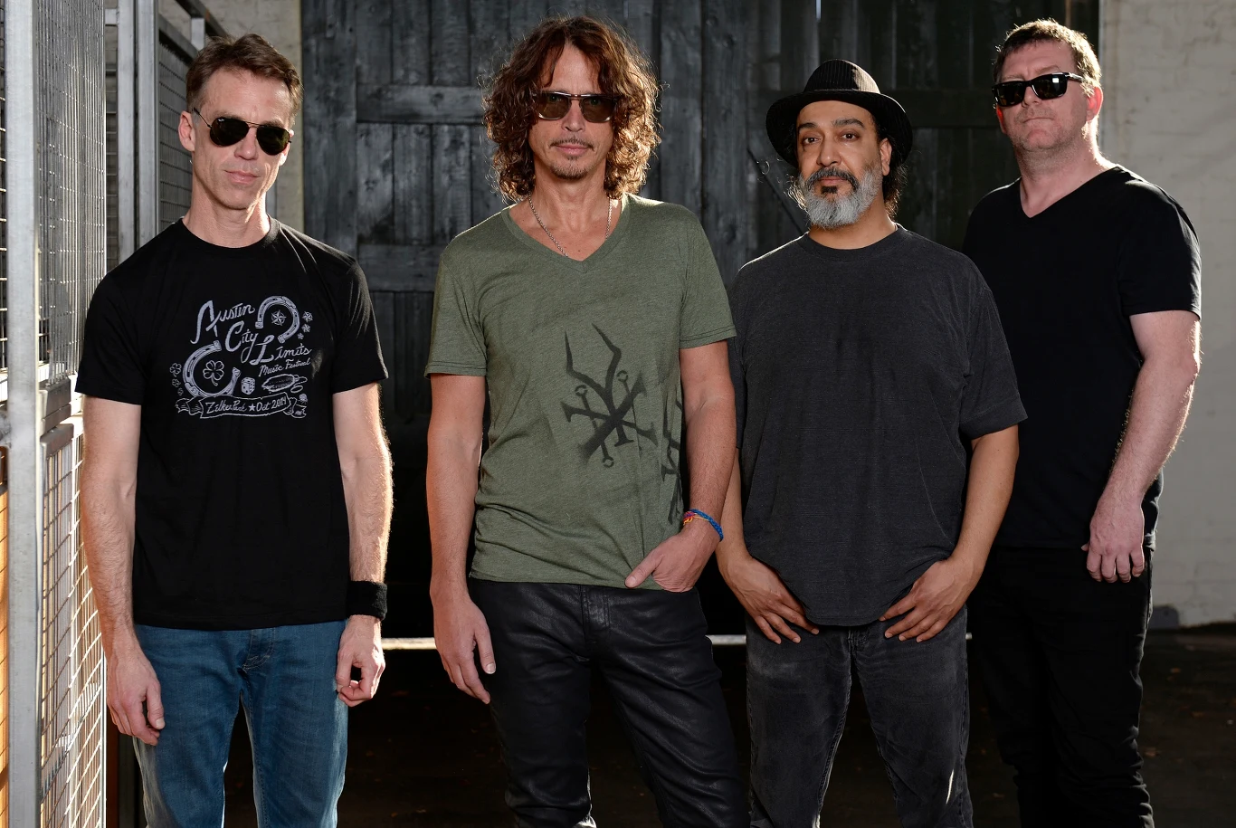 Soundgarden w 2015 r. - od lewej: Matt Cameron, Chris Cornell, Kim Thayil i Ben Shepherd Czterech mężczyzn stoi razem przed drewnianymi drzwiami w swobodnych pozach, każdy z nich nosi okulary przeciwsłoneczne i casualowe ubrania, jeden z mężczyzn ma kapelusz, a pozostali krótkie fryzury.