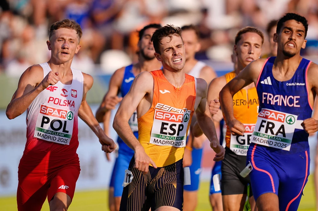Grupa lekkoatletów biegnących w trakcie zawodów, widoczni sportowcy w strojach reprezentacyjnych Polski, Hiszpanii, Niemiec i Francji, skupieni w rywalizacji na bieżni, wyraźne emocje na ich twarzach, trybuny w tle.