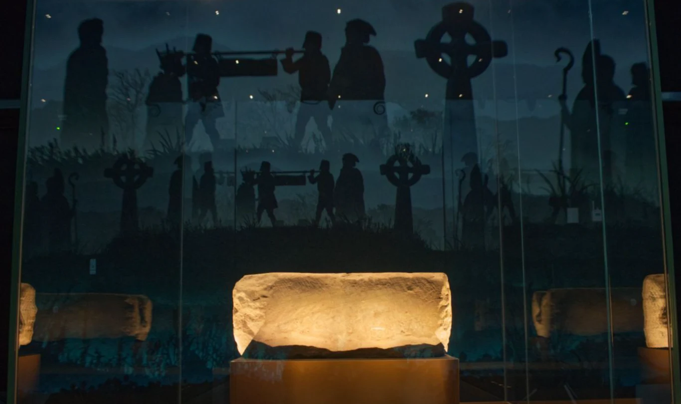 Australijczyk w kilcie zaatakował Kamień Przeznaczenia. Nie udało mu się uszkodzić artfekatu Kamienna płyta nagrobna podświetlona w muzealnej gablocie z widocznym w tle malowidłem lub instalacją ukazującą procesję pogrzebową, sylwetki ludzi niosących trumnę oraz liczne krzyże celtyckie i pastorał.