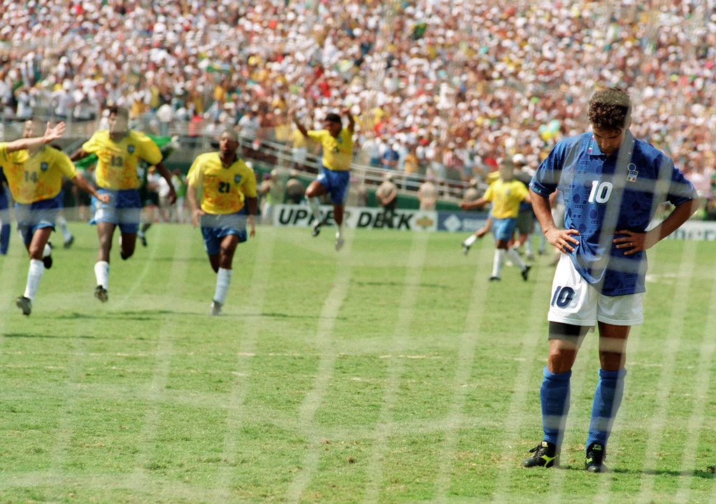 Jedno z najsłynniejszych zdjęć w historii piłkarskich mistrzostw świata. Roberto Baggio spuszcza głowę po przestrzelonym rzucie karnym, w tle Brazylijczycy świętują wywalczenie swojego czwartego tytułu na mundialu Jedno z najsłynniejszych zdjęć w historii piłkarskich mistrzostw świata. Roberto Baggio spuszcza głowę po przestrzelonym rzucie karnym, w tle Brazylijczycy świętują wywalczenie swojego czwartego tytułu na mundialu