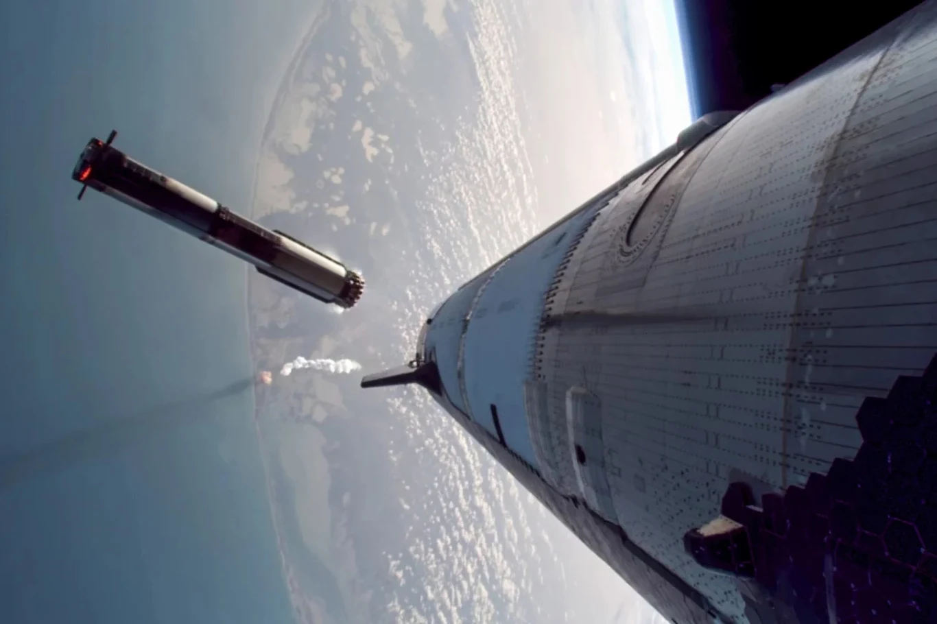 Elon Musk zapowiada powrót Starshipa. SpaceX wkrótce wznowi testy rakiety. Moment oddzielenia pierwszego stopnia rakiety kosmicznej ujęty nad powierzchnią Ziemi, na tle krzywizny planety widoczny jest ciemny, odłączający się segment rakiety oraz statek zmierzający na orbitę