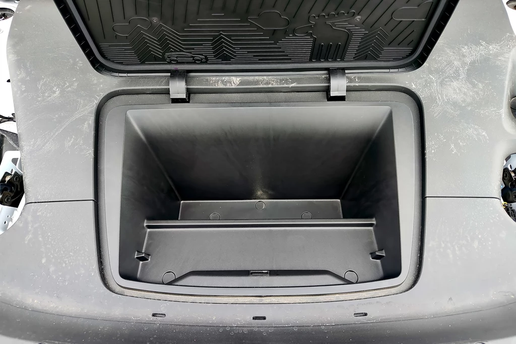 Frunk, czyli schowek pod maską Volvo EX30 ma tylko 7 litrów Otwarty bagażnik przedni samochodu elektrycznego z wyraźnie widoczną dużą, pustą przestrzenią oraz plastikową osłoną umożliwiającą łatwe przechowywanie przedmiotów.